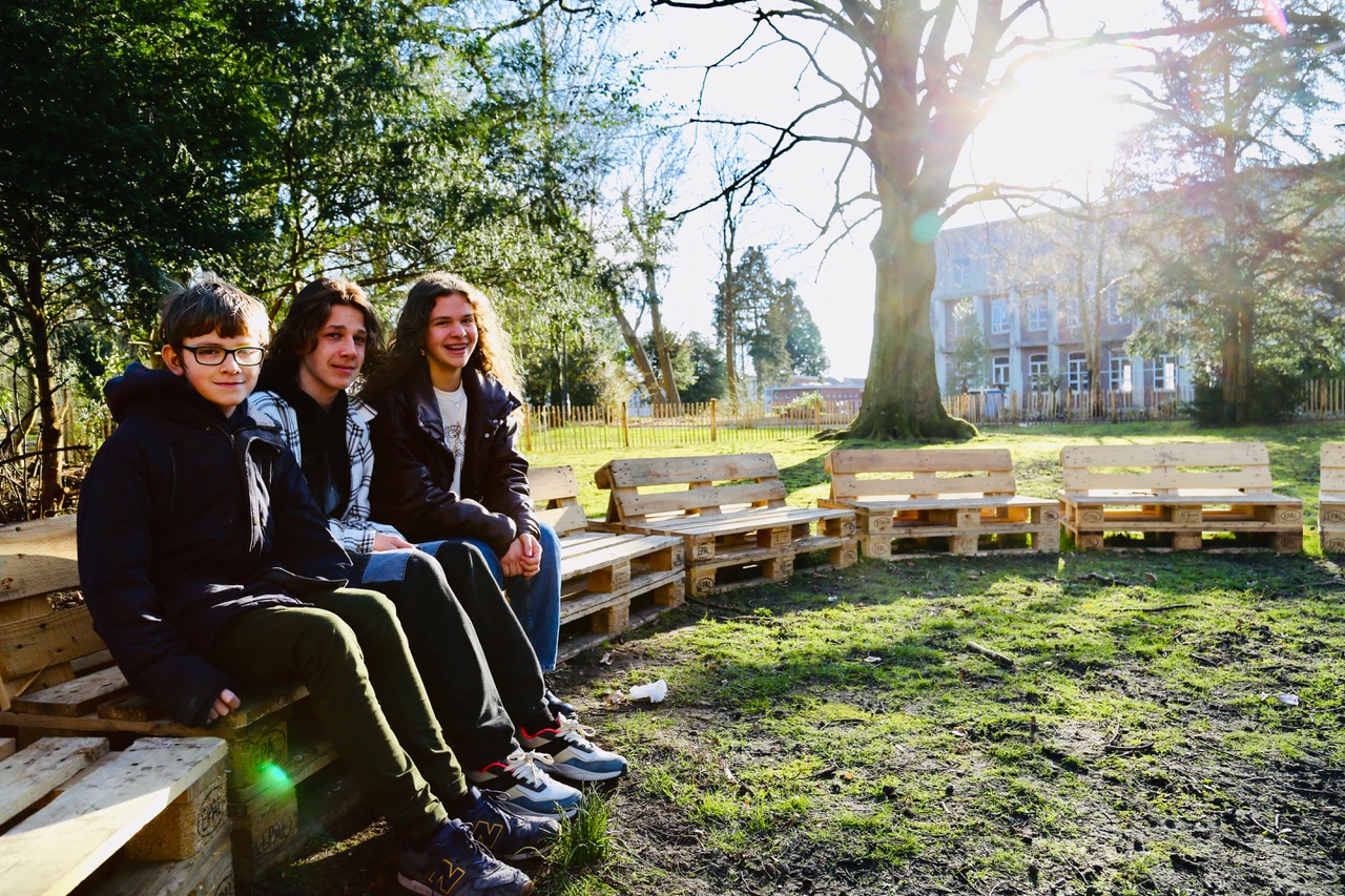 drie kinderen_zitten op bank_inde tuin van collegetendoorn